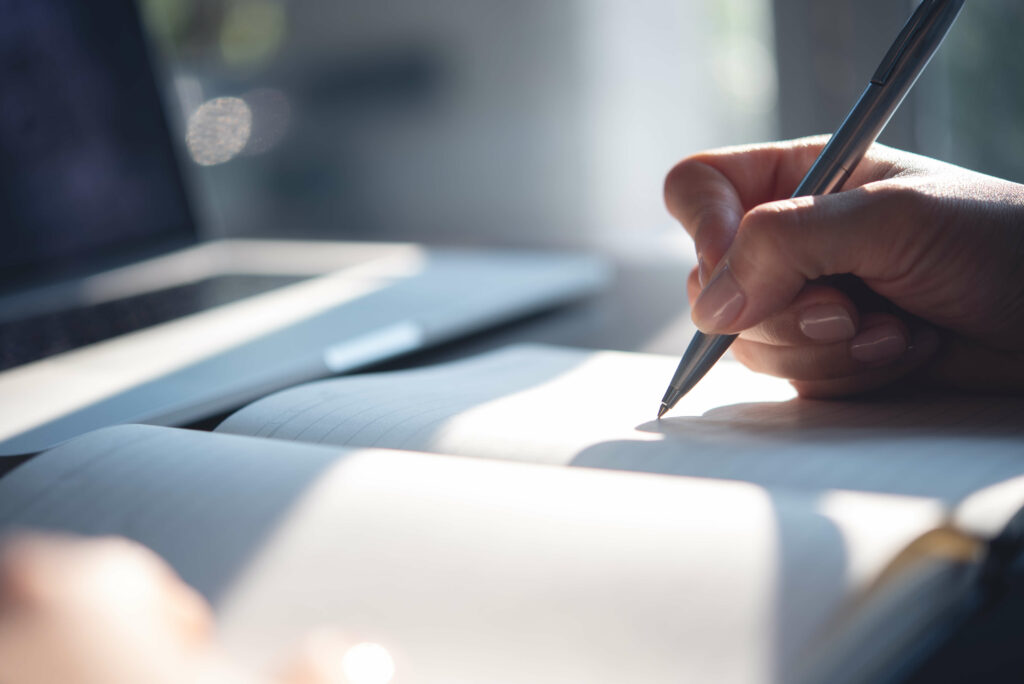 Personne qui prend un rendez-vous sur son agenda papier avec un stylo bille